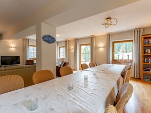 Enjoy meals with friends and family at the dining table, surrounded by comfortable seating and a bookshelf filled with reading material.