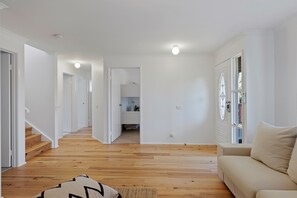 A spacious hallway with wooden flooring, a beige sofa, and a staircase leading to another room. - Renovated open planned living sun drenched house in Cape Woolamai (Cape Woolamai)
