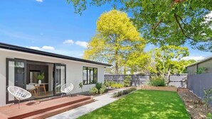 A modern house with a patio, a lawn, and a tree.