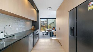 A modern kitchen with a black countertop, stainless steel appliances, and a view to a balcony. - Latimer View Apartment (Christchurch)