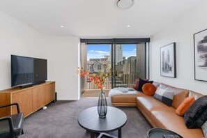 Een moderne woonkamer met een flatscreen televisie, een bank, een salontafel en uitzicht door een schuifdeur.