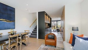 A modern living room with a dining area, a staircase, and a kitchen in the background. - Latimer View Apartment (Christchurch)
