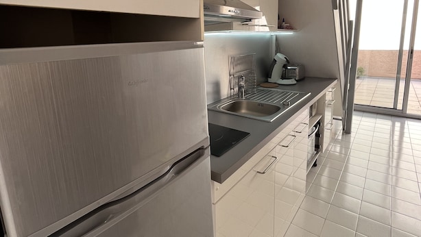 Uma cozinha moderna com eletrodomésticos de aço inoxidável, forno embutido e uma ampla janela que oferece iluminação natural.