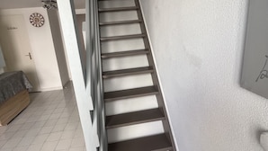A staircase with a handrail, a door labeled "Bathroom," and a wall clock.