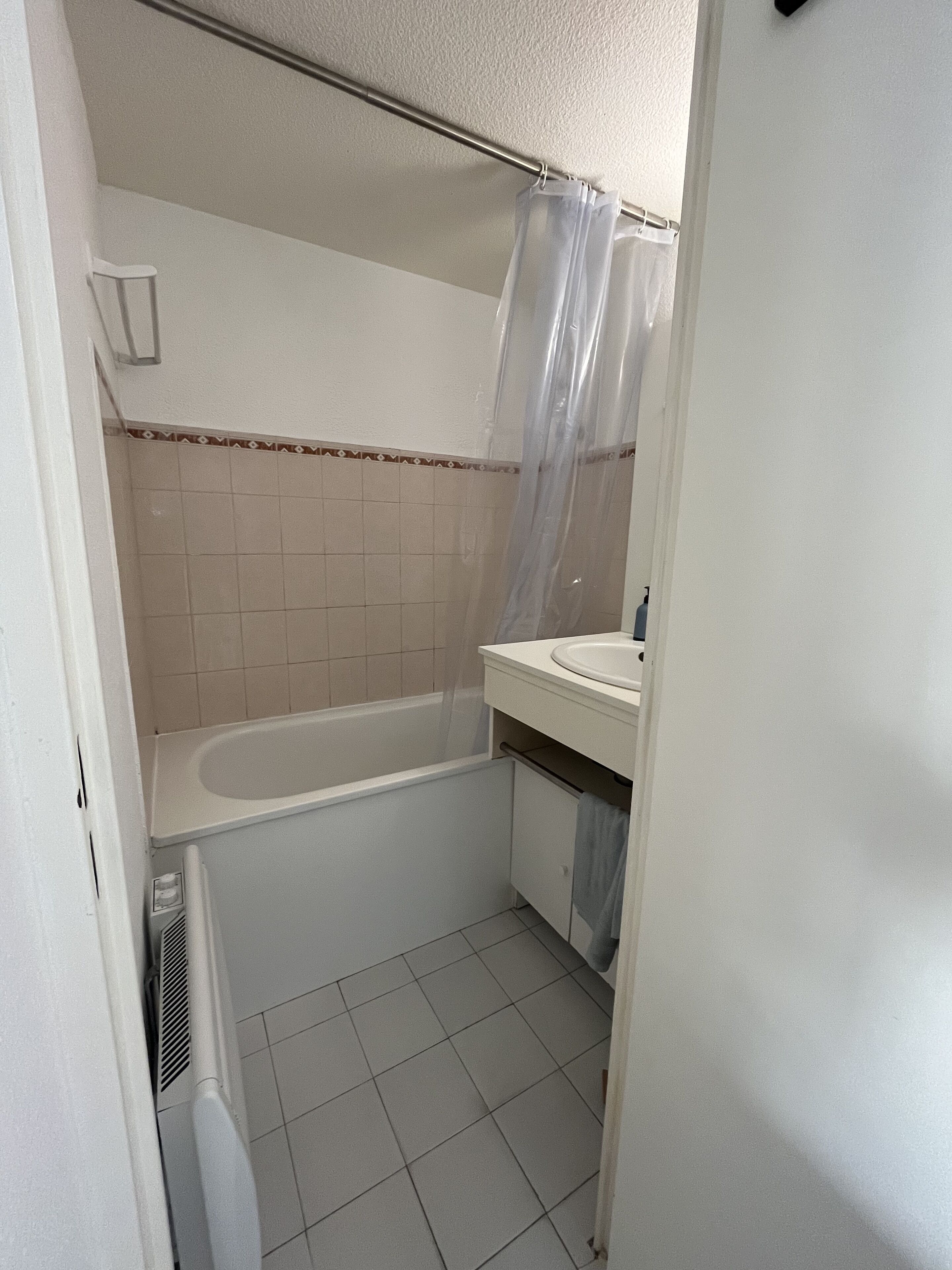 A small, clean bathroom with a bathtub, a sink, and a shower curtain.