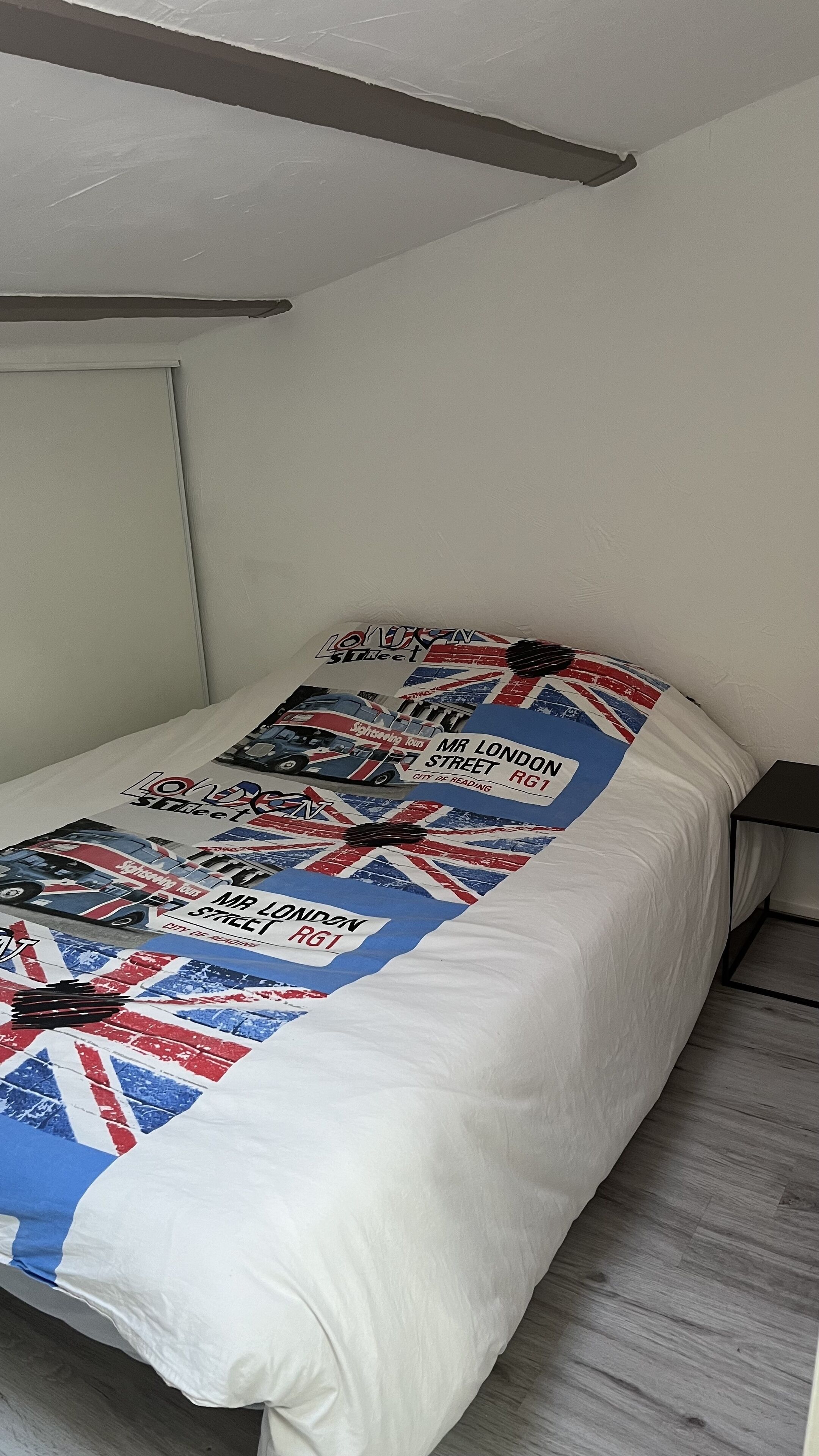 A single bed with a white mattress and a patterned blanket.