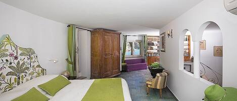 A bedroom with a bed, a wooden wardrobe, a chair, and a window.