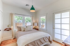 A bedroom with a bed, bedside tables, and a window.