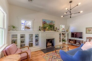 A living room with a fireplace, bookshelves, a television, and seating.