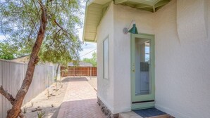Una casa con puerta verde, un pequeño porche y un árbol en primer plano.