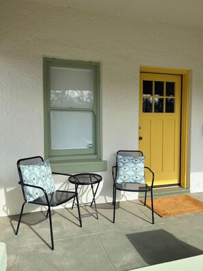 A porch with two chairs and a table, a yellow door, and a window with a green frame. - Remodeled Gem 5 minutes to UA (Tucson)