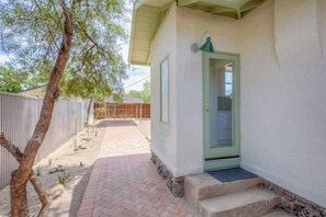 A house with a green door, a covered patio, and a fenced backyard.