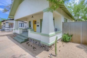 A single-story house with a covered porch, a yellow door, and a small garden area with a cactus. - Remodeled Gem 5 minutes to UA (Tucson)