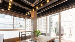 A modern workspace with a wooden table, chairs, and a potted plant. - Tabist MAYUDAMA CABIN (Yokohama)