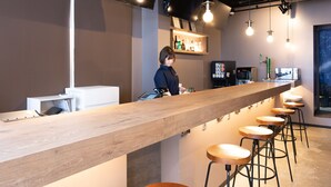 A bar area with a long counter, stools, and hanging lights. - Tabist MAYUDAMA CABIN (Yokohama)