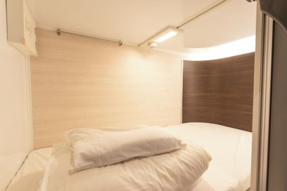 A hotel room with a bed, a wooden headboard, and a window.