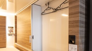 A hotel room with a wooden floor, a bed, a wardrobe, and a control panel. - Tabist MAYUDAMA CABIN (Yokohama)