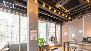 A modern interior with a wooden floor, a large window, a plant, and a no-smoking sign. - Tabist MAYUDAMA CABIN (Yokohama)