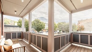 A covered outdoor area with wooden flooring, a bench, and a view of the street and buildings. - Walk to Rhinegeist | Findlay Market| Streetcar (Cincinnati)