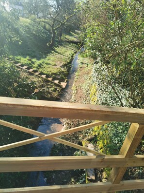 Eine Holzbrücke über einen Bach, umgeben von üppigem Grün.