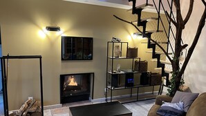 Un salon avec une cheminée, un escalier et une table basse.