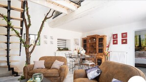 Un salon moderne avec un escalier, deux canapés, une table basse et un coin repas.
