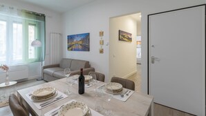 Un comedor con una mesa dispuesta para cuatro, un sofá y una puerta que da a otra habitación.