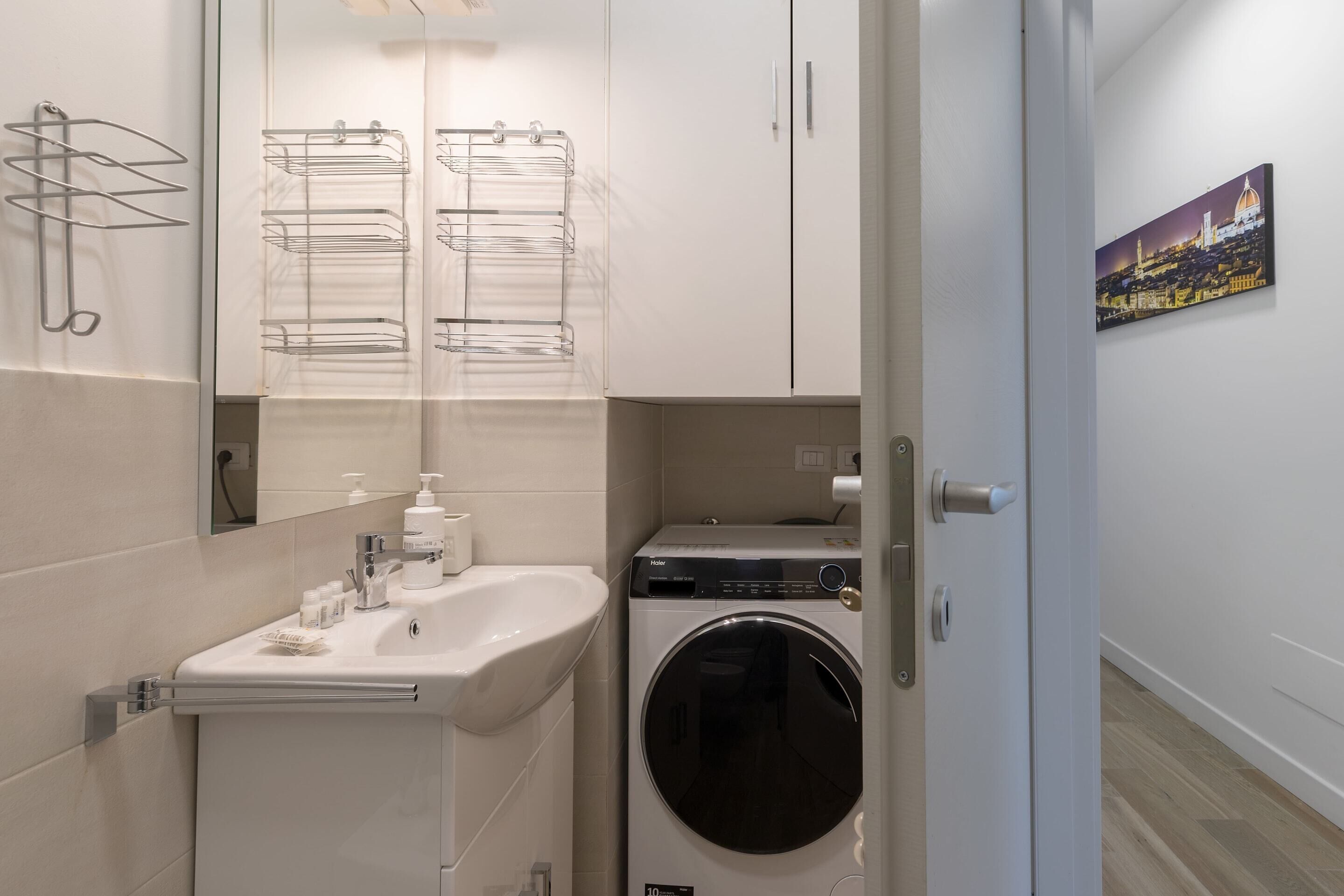Une petite salle de bain comprenant un lavabo, un miroir, un lave-linge et un porte-serviettes.