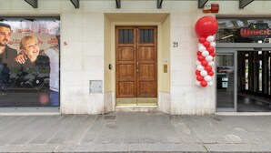 Una entrada de edificio con puerta doble de madera, el número '21' arriba y una decoración de globo rojo y blanco a la derecha.