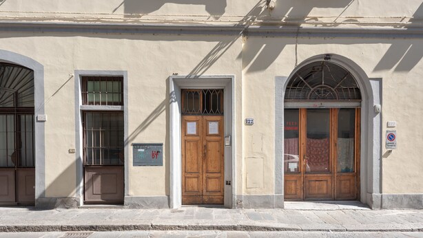 A building facade with three wooden doors, each with a window above. - Sanzanobi Apartment (Florence)