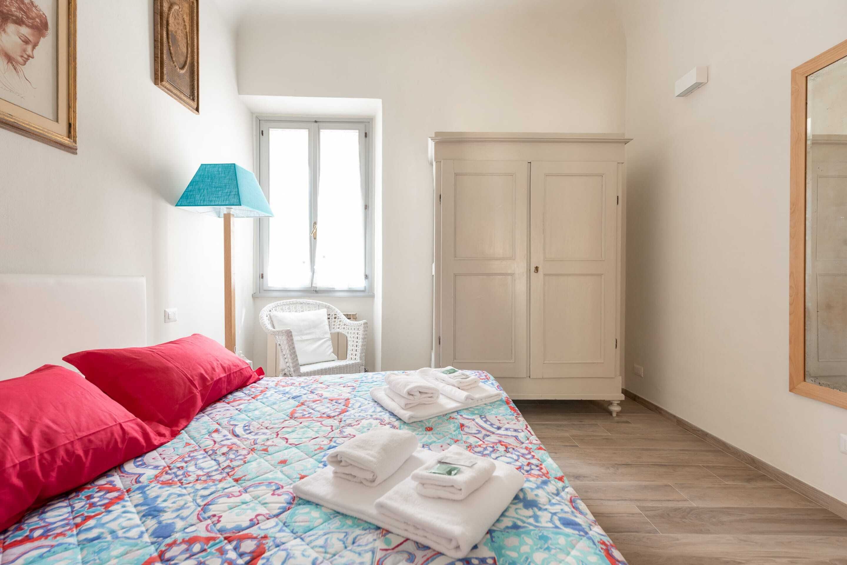 Een slaapkamer met een bed, een kledingkast, een stoel en een lamp.