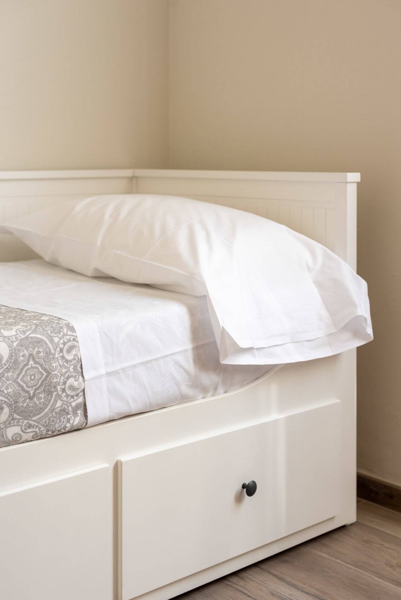 A bed with a white headboard and a single drawer below.