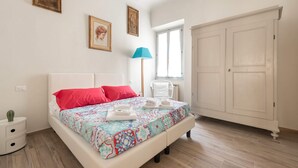 A bedroom with a bed, a nightstand, a lamp, a wardrobe, and a window. - Sanzanobi Apartment (Florence)
