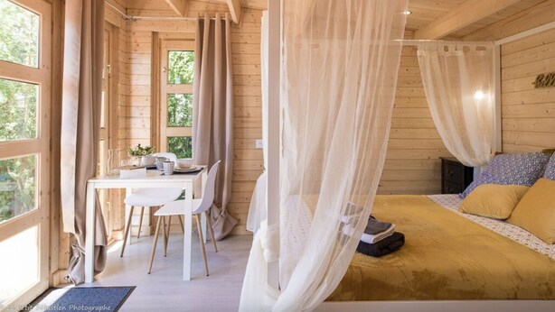 Ein Schlafzimmer in einer Holzhütte mit einem Bett, einem Tisch und Stühlen.