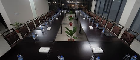 Un salón de conferencias con una larga mesa, sillas, botellas de agua y tarjetas de identificación.