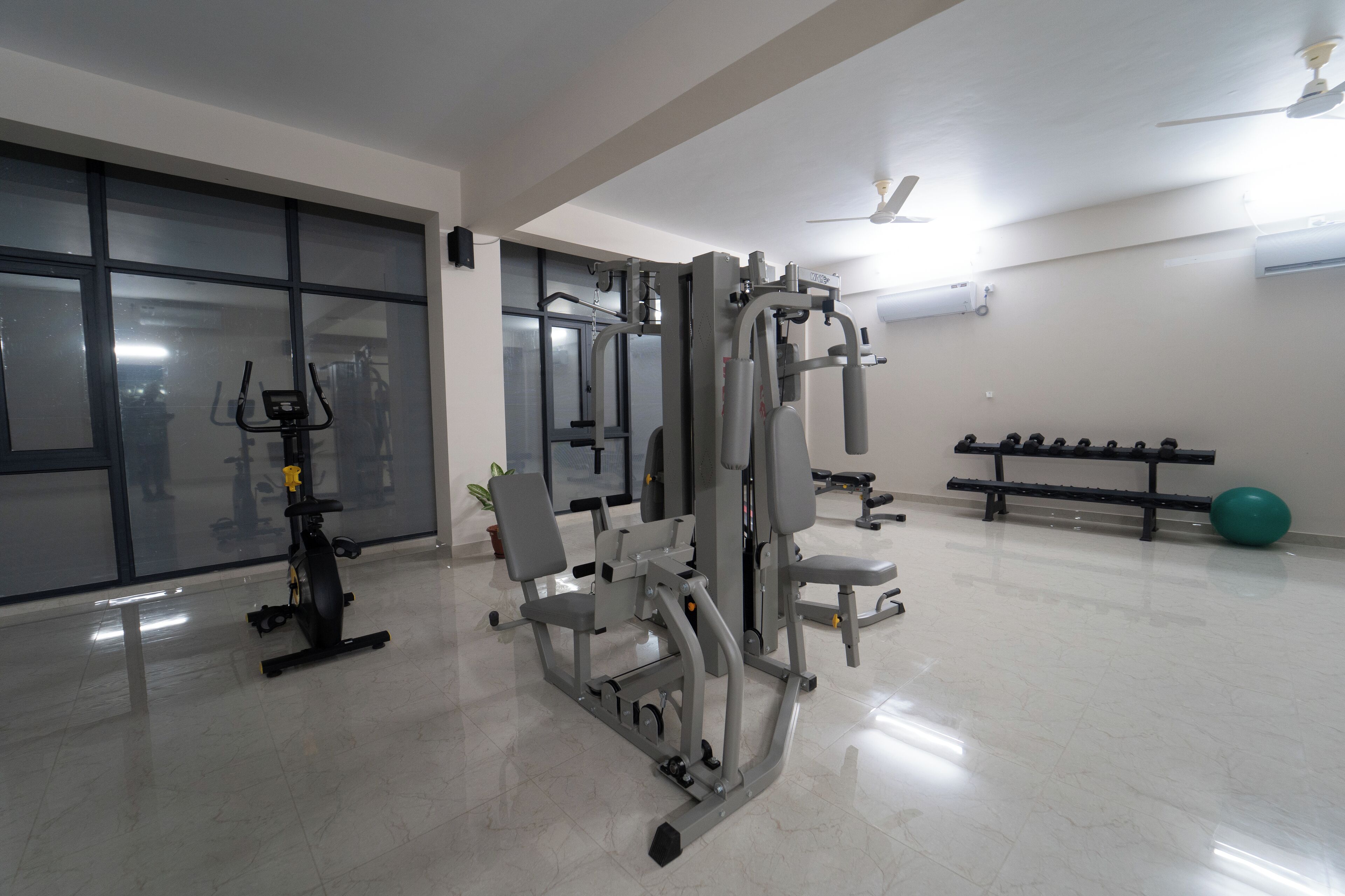 Un gimnasio con equipo de ejercicio, una banca y una pelota de ejercicio verde.