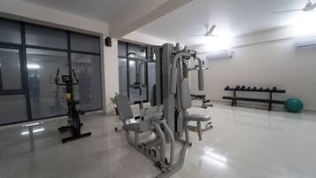 Un gimnasio con equipo de ejercicio, una banca y una pelota de ejercicio verde.
