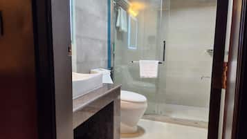 A modern bathroom with a glass shower enclosure, a white toilet, and a vanity with a marble countertop.