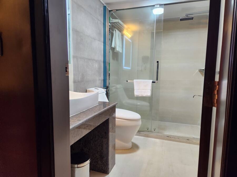 A modern bathroom with a glass shower enclosure, a white toilet, and a vanity with a marble countertop.