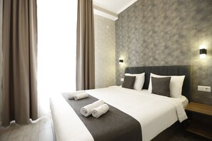 A neatly made bed with white and dark gray linens, a wooden nightstand, and a textured wall. - Urban Hotel (Bishkek)
