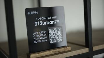 Ein schwarzes Schild mit einem QR-Code und kyrillischer Schrift, an einem Holzboden angebracht.