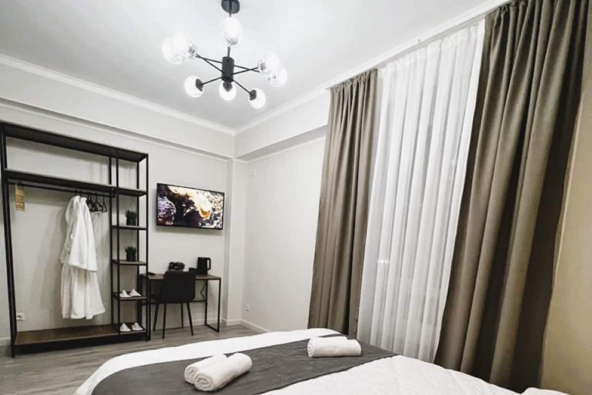 A hotel room with a bed, a desk, a chair, a TV, and a wardrobe.