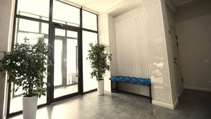A spacious room with large windows, a bench, and two potted plants. - Urban Hotel (Bishkek)