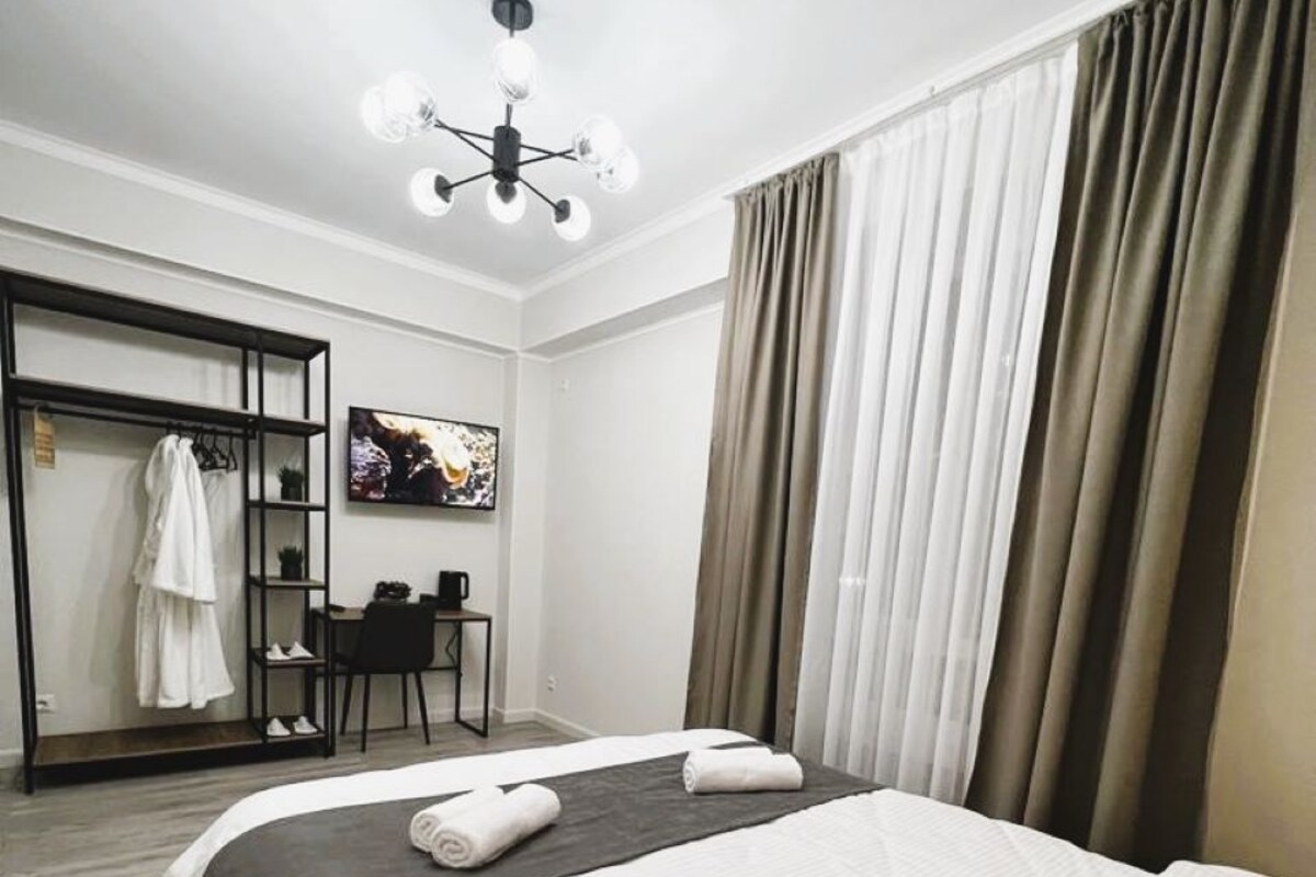 Une chambre d’hôtel comprenant un lit, un bureau, une chaise, une télévision et une armoire.