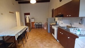 A compact kitchen with a dining table and chairs, a refrigerator, stove, and a sink.