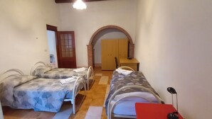 A room with two beds, a wooden wardrobe, and a small table.