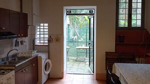 A compact kitchen with a washing machine, a sink, and a stove. There is a door leading to an outdoor area with a table and chairs.