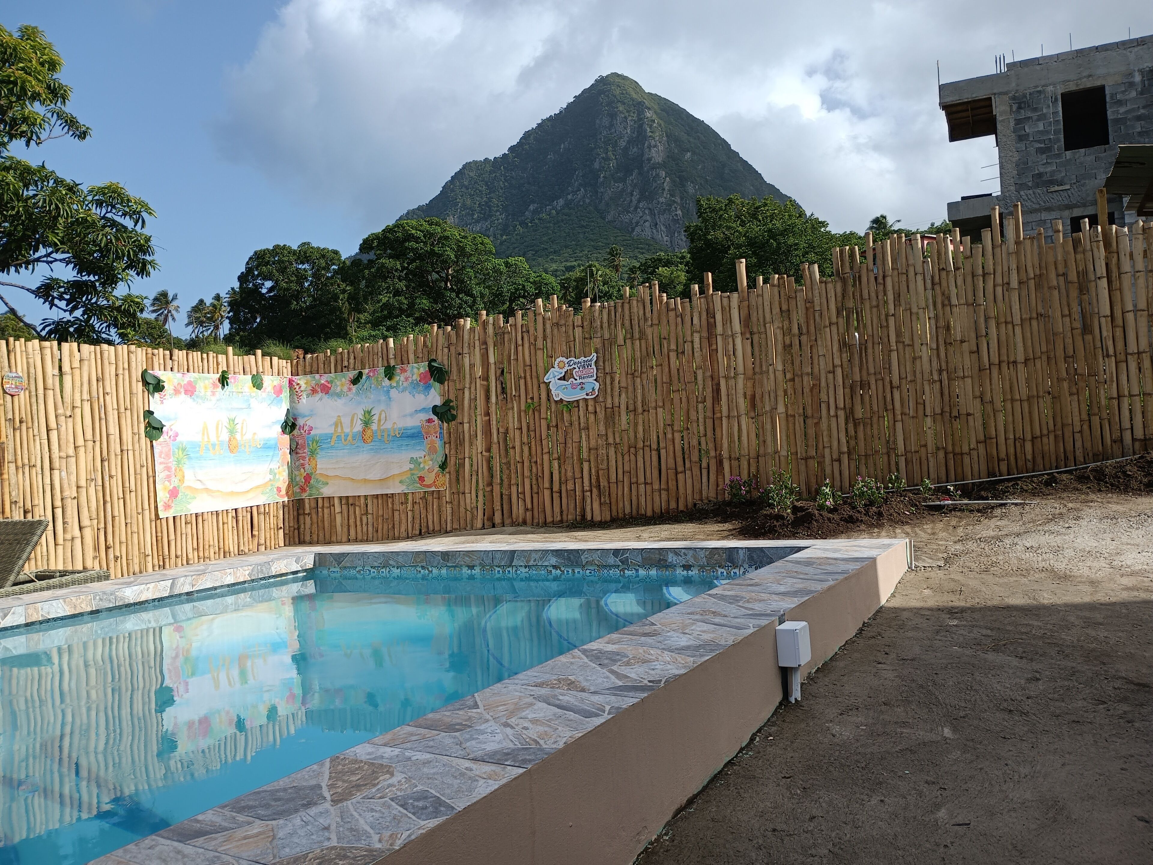 Una piscina con una recinzione in bambù e uno striscione a tema tropicale.