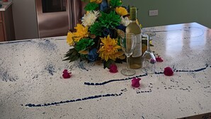Eine Küche mit einem Edelstahl-Kühlschrank, einem Blumenstrauß aus künstlichen Blumen, einer Weinflasche und einem Glas auf der Arbeitsplatte.