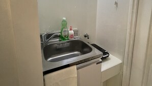 Pieni kylpyhuone, jossa on pesuallas, peili ja pyyhe, joka on ripustettu oveen.